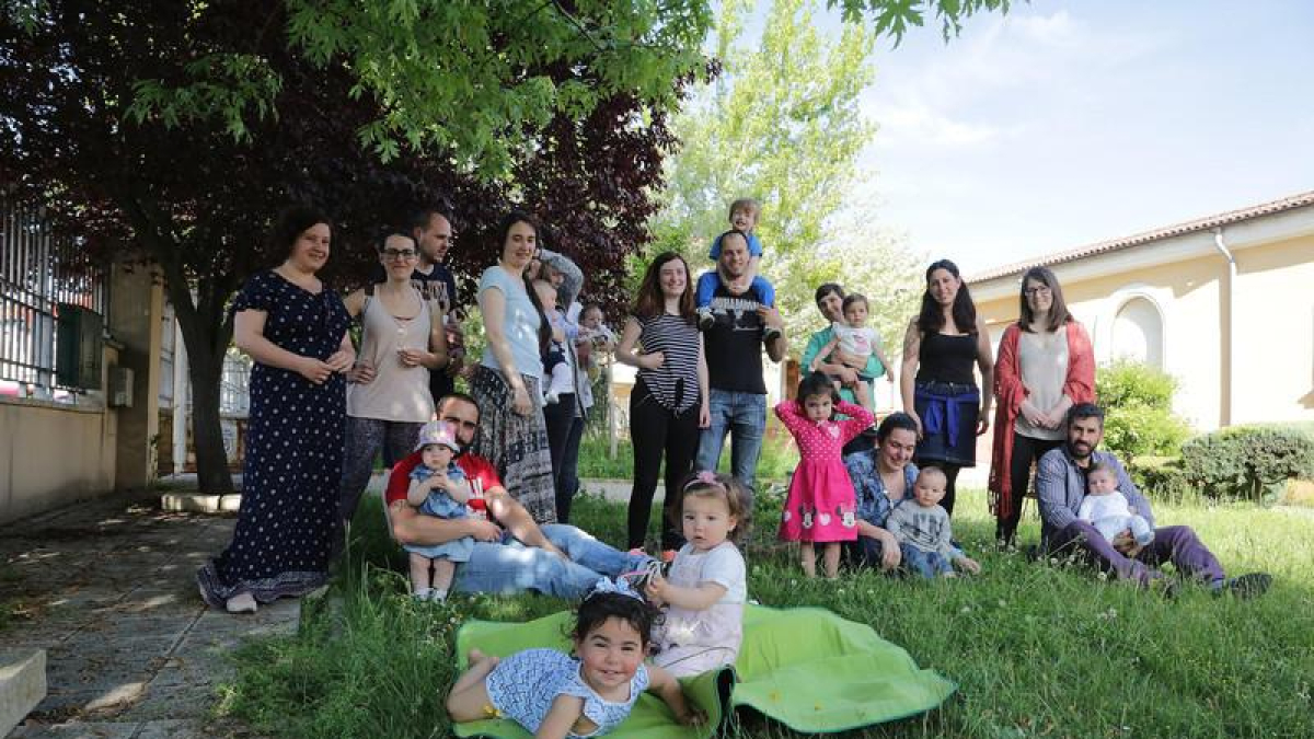 Padres y madres de la asociación 'Creciendo Juntos' posan con sus hijos en un jardín de Puente Castro.