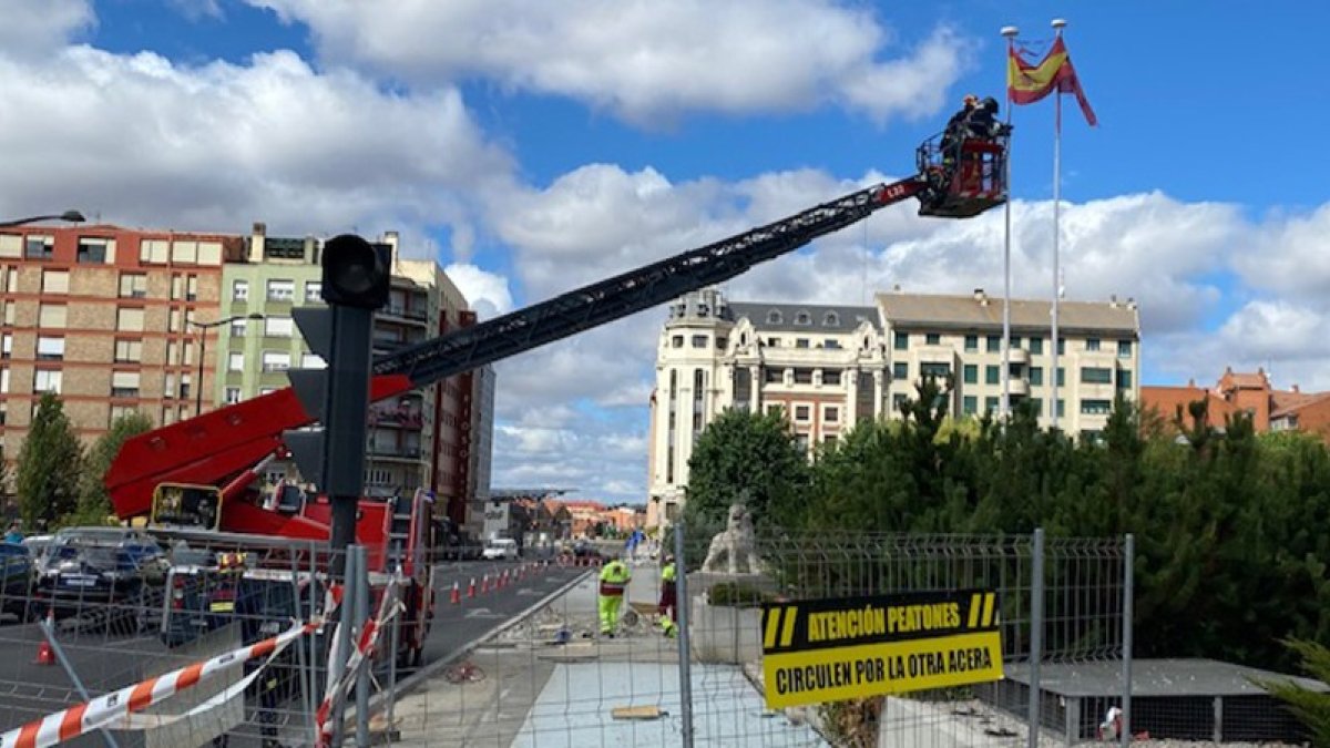 Los bomberos de León sustituyen las banderas de España y de León situadas en la entrada a León por el puente de Los Leones.