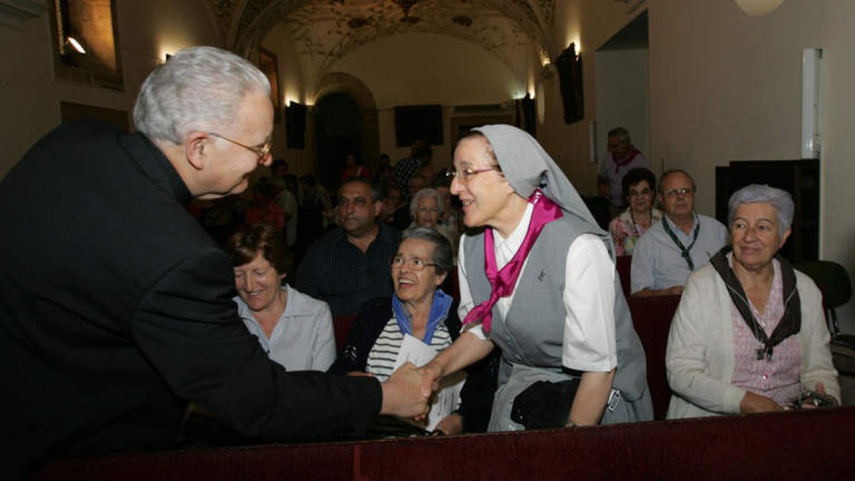 El obispo de León, Julián López, saluda a una de las misioneras durante su llegada al Salón del Pendón.