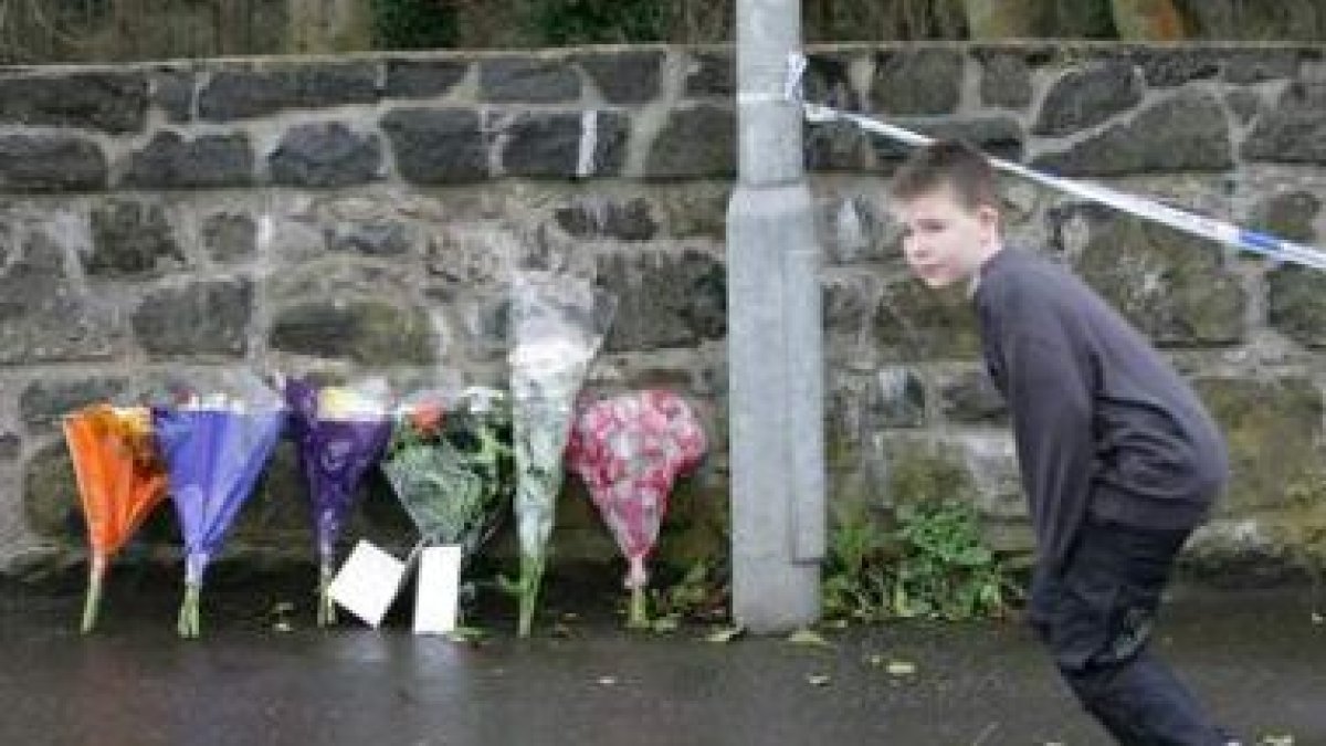 Un niño pasa cerca de la entrada principal a la base militar británica de Massereene donde ocurrió e
