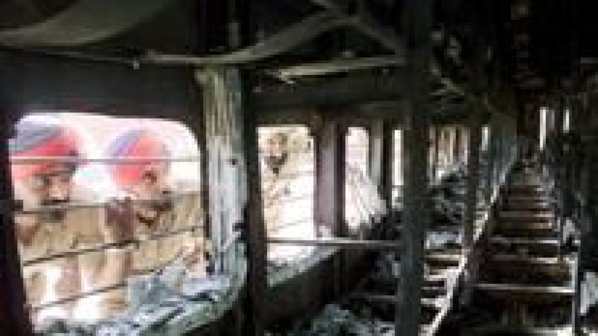Dos hombres miran por la ventana de uno de los vagones afectados, que quedó completamente destruido