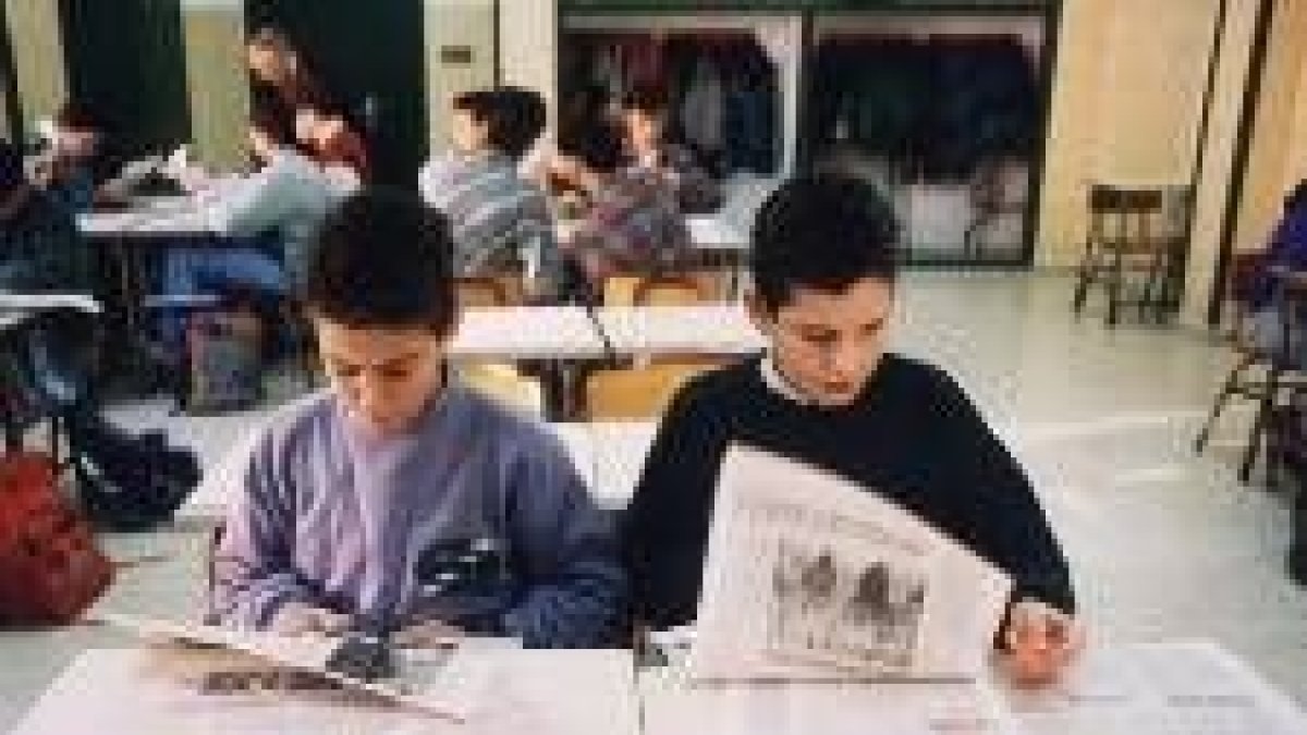 Los niños recortan noticias de un periódico para sus actividades de la escuela