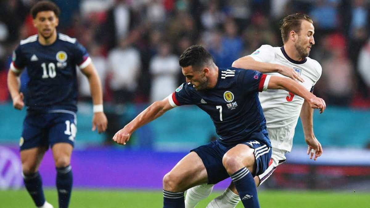 El delantero inglés Harry Kane pelea por el balón con el escocés John McGinn. JUSTIN