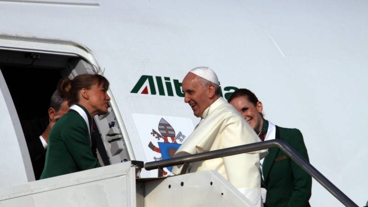 Una azafata da la bienvenida al Papa al subir a bordo del avión que le traslada a Brasil.
