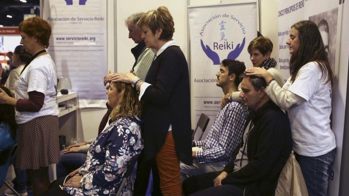 Un grupo de personas se somenten a una sesión de Reiki, considerada una pseudoterapia, en el parque ferial de Madrid