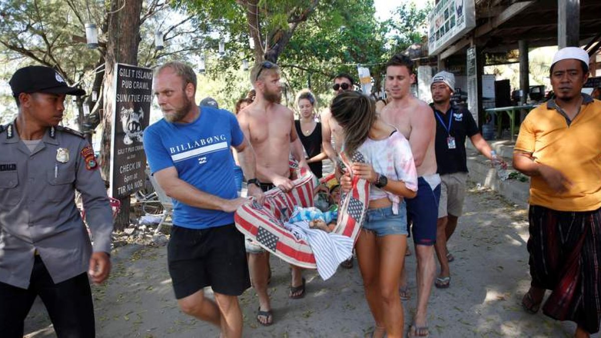 Turistas ayudan a una mujer herida tras el terremoto que sacudió la isla de Lombok. ADI WEDA