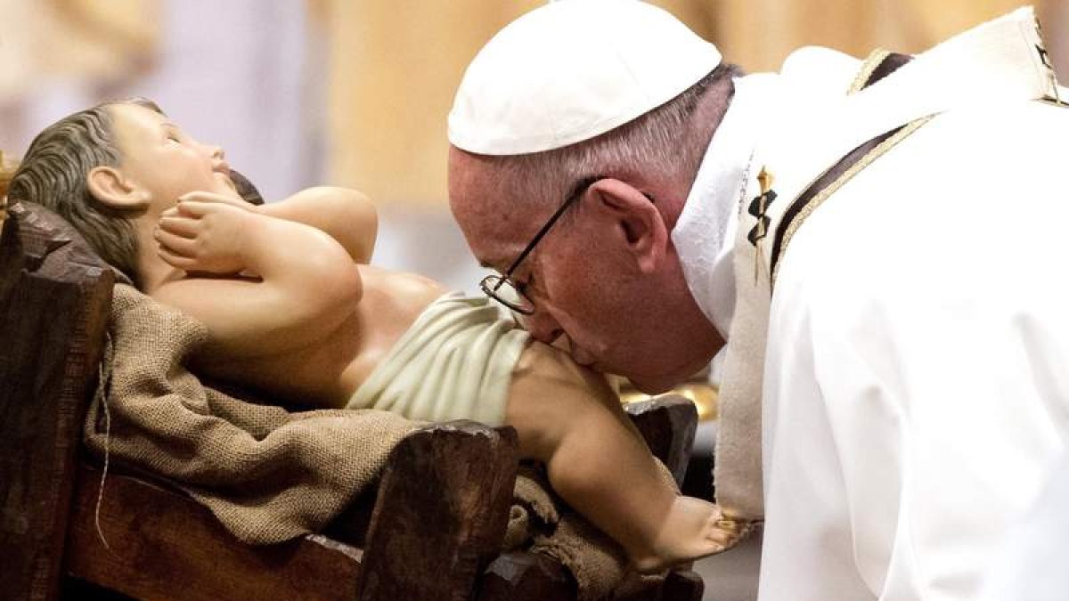 El papa besa la figura del niño Jesús durante la misa de Navidad en el Vaticano. CLAUDIO PERI
