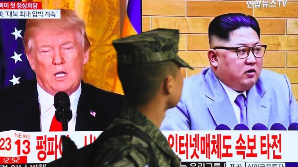 Un soldado surcoreano pasa frente a un televisor en Seúl mientras aparecen en la pantalla Donald Trump y Kim Jong un.