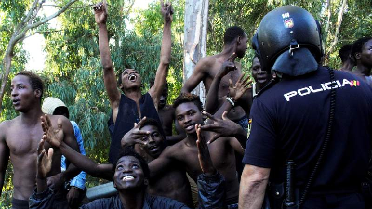 Los inmigrantes muestran su júbilo tras cruzar la valla. REDUAN