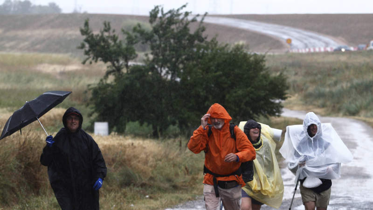 La lluvia sorprende a unos peregrinos a su paso por León.
