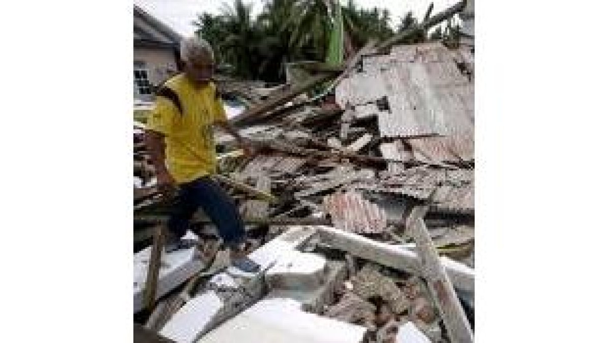 Un superviviente del terremoto camina entre los escombros de su casa