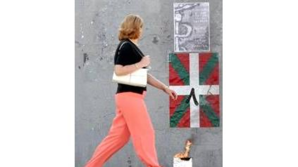 Una mujer pasa ante una ikurriña y el anagrama de ETA, ayer en Bilbao