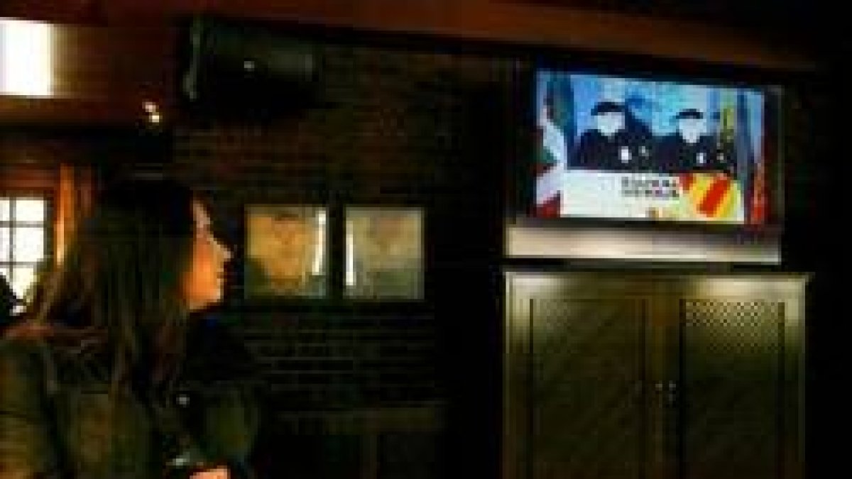 Una mujer atiende al comunicado de la banda en un bar de Vitoria