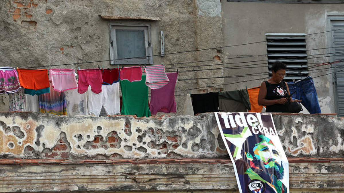 Una mujer en un balcón junto a un cartel con la imagen de Fidel Castro en La Habana. ALEJANDRO ERNESTO