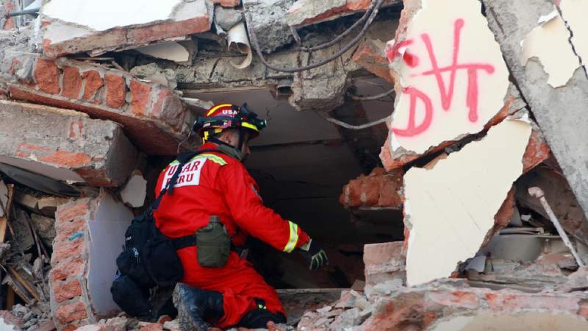 Un bombero peruano trata de escuchar si hay gente atrapada en el edificio. CHRISTIAN ESCOBAR MORA