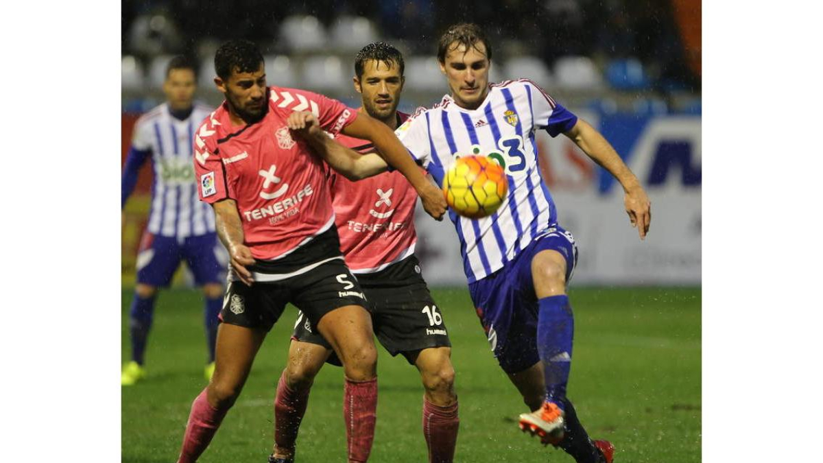 Ignasi Miquel intenta controlar el balón ante la acción de dos jugadores del CD Tenerife.