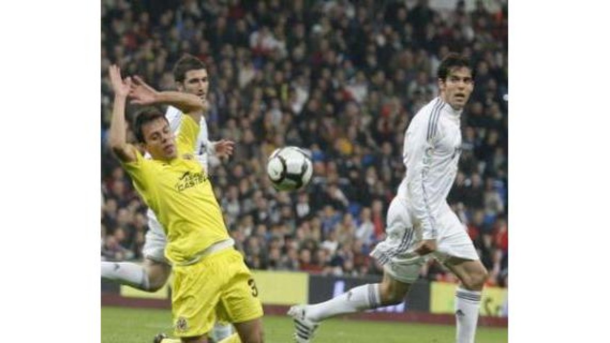 Kaka mira la dirección que toma su lanzamiento ante la oposición de Fuster y la mirada de Higuaín.