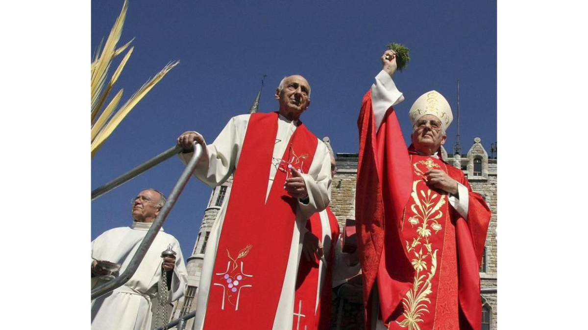 El obispo de León, Julián López (C), bendice las palmas en la celebración del Domingo de Ramos
