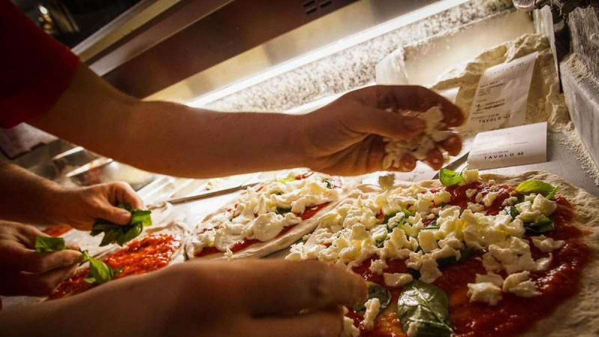 Un restaurante de comida rápida prepara pizzas para llevar a casa. CÉSAR ABBATE