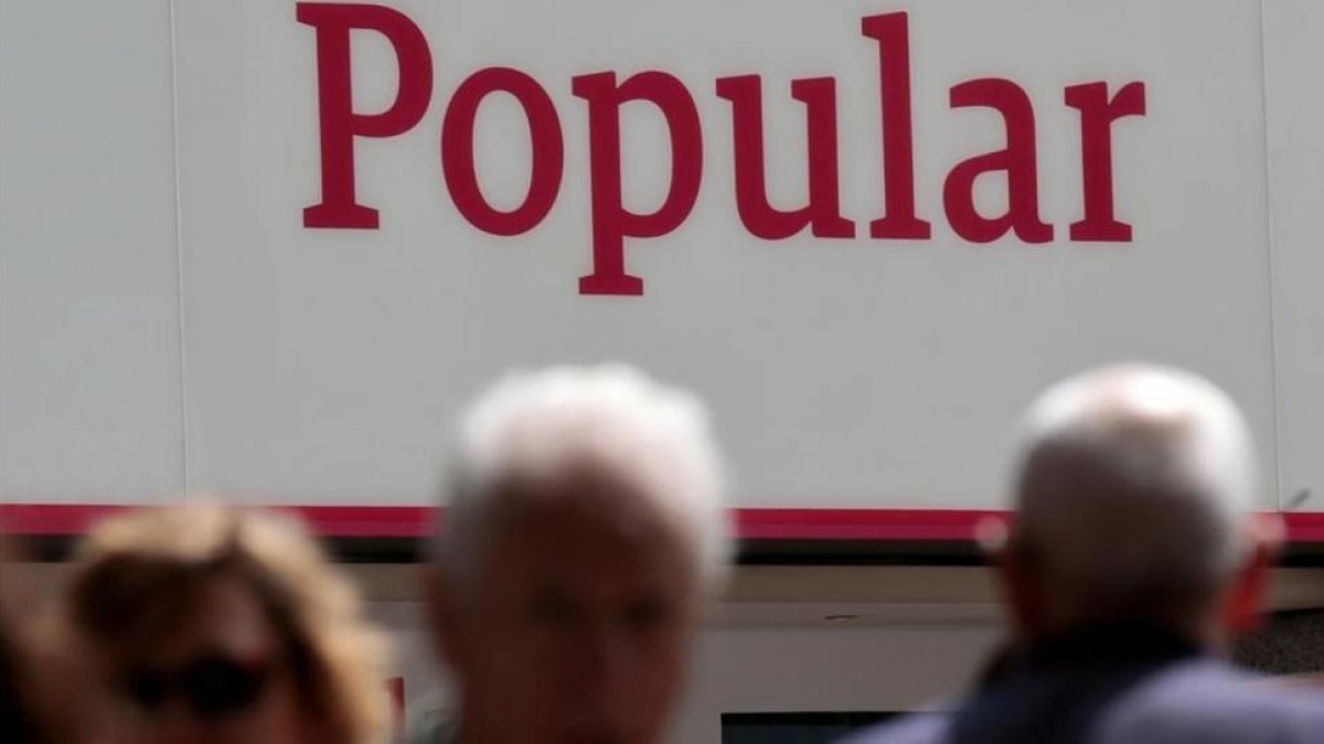 Personas caminando por delante de una oficina del Banco Popular en Madrid.