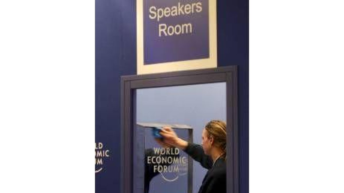 Un trabajador limpia un espejo en el lugar donde se celebra el foro