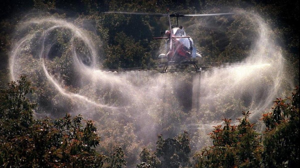 Un aspersor riega con pesticidas un campo de cultivo.