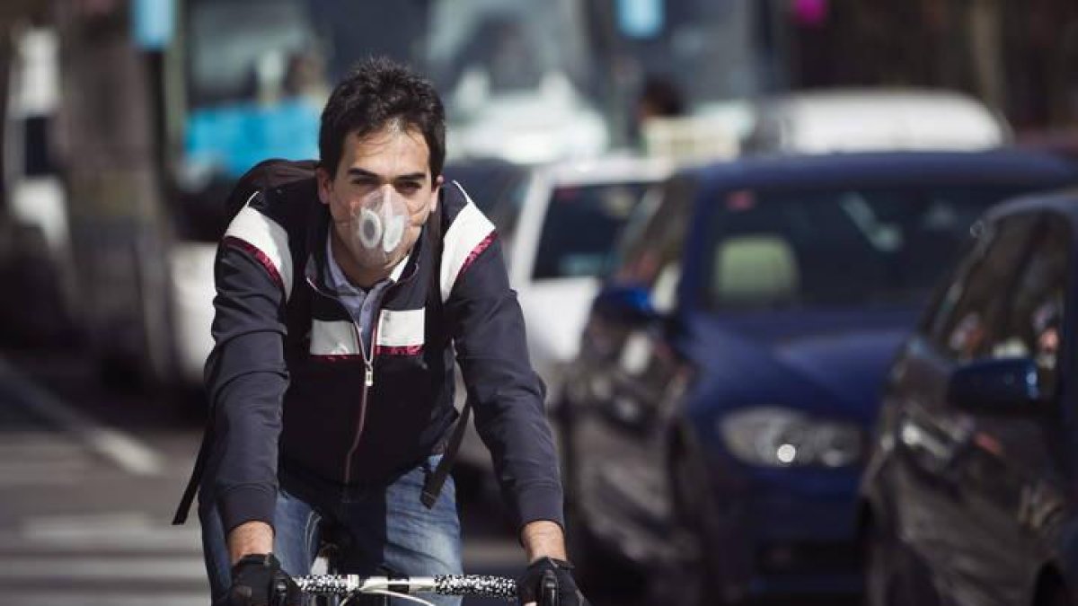 un ciclista con una mascarilla circulando hoy por las calles de Madrid