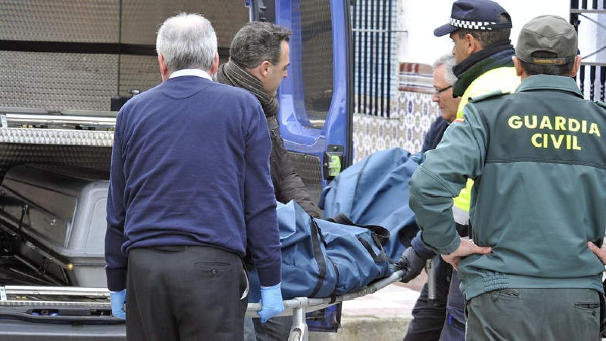 Varios operarios trasladan uno de los cuerpos sin vida.