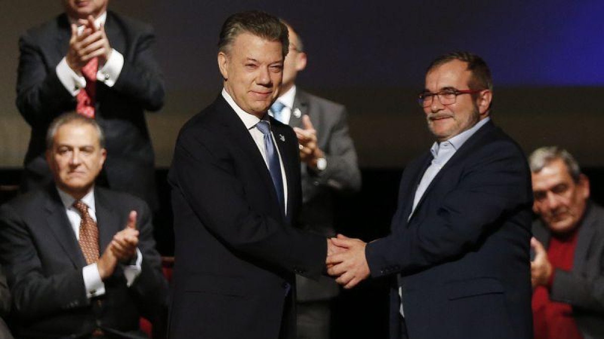 Santos (izquierda) y Rodrigo Londoño, alias 'Timochenko', se dan la mano tras firmar el nuevo acuerdo, en Bogotá, este jueves.