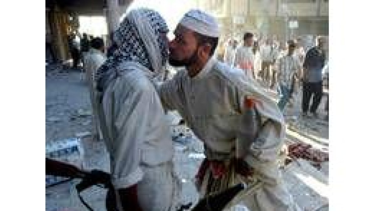 Un fiel chií besa a un miliciano de Al Sáder en los alrededores de la mezquita de Nayaf