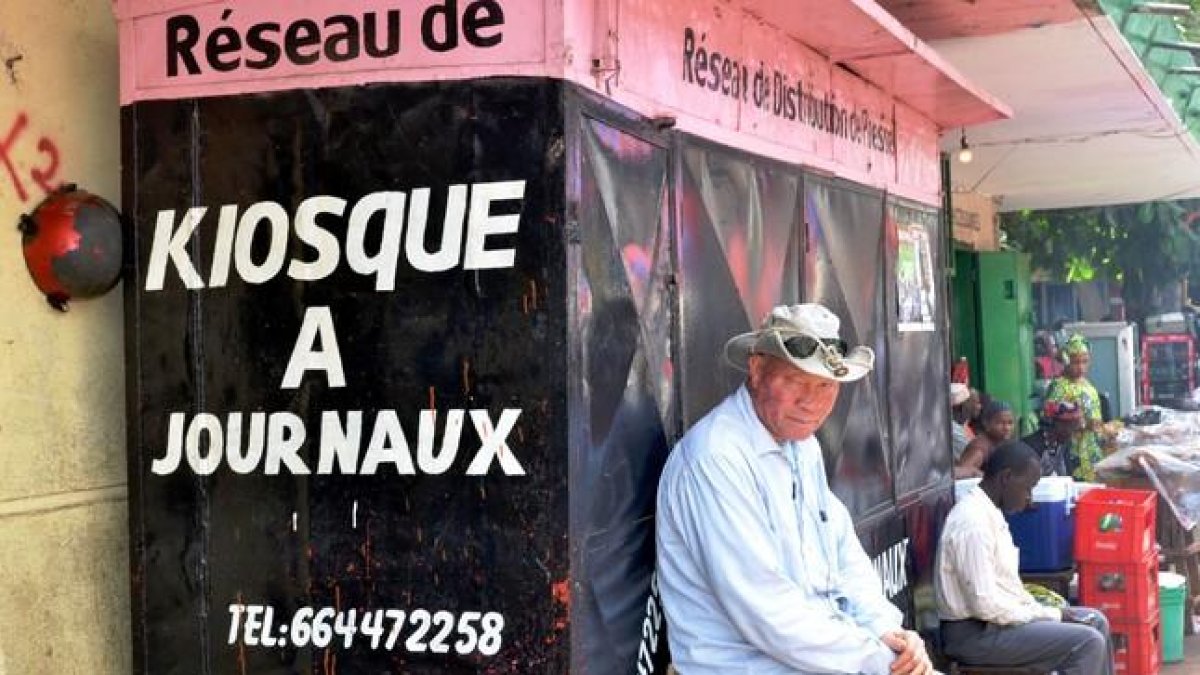 Un hombre sentado delante de un quiosco cerrado en Guinea.