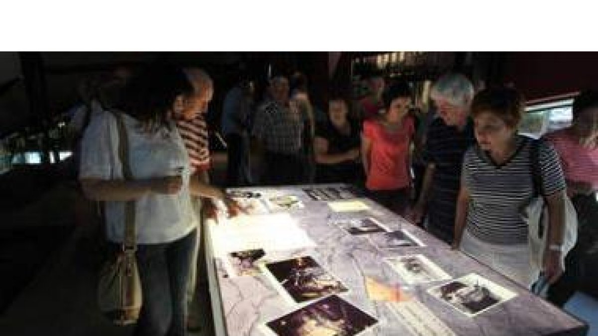 Un grupo de visitantes contempla uno de los paneles con fotografías antiguas.