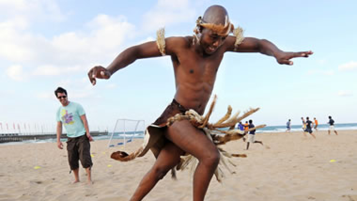 Un niño africano juega con un balón en la playa.
