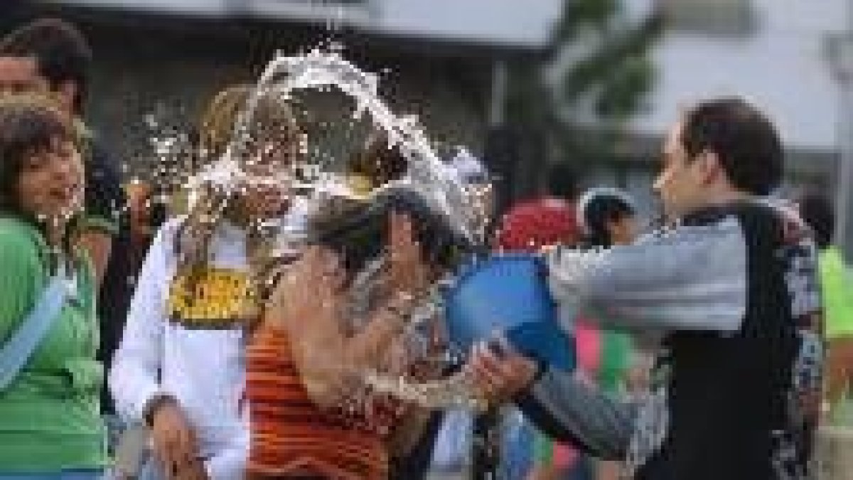 Un joven lanza un caldero de agua a una chica ayer durante la celebración de la fiesta del agua
