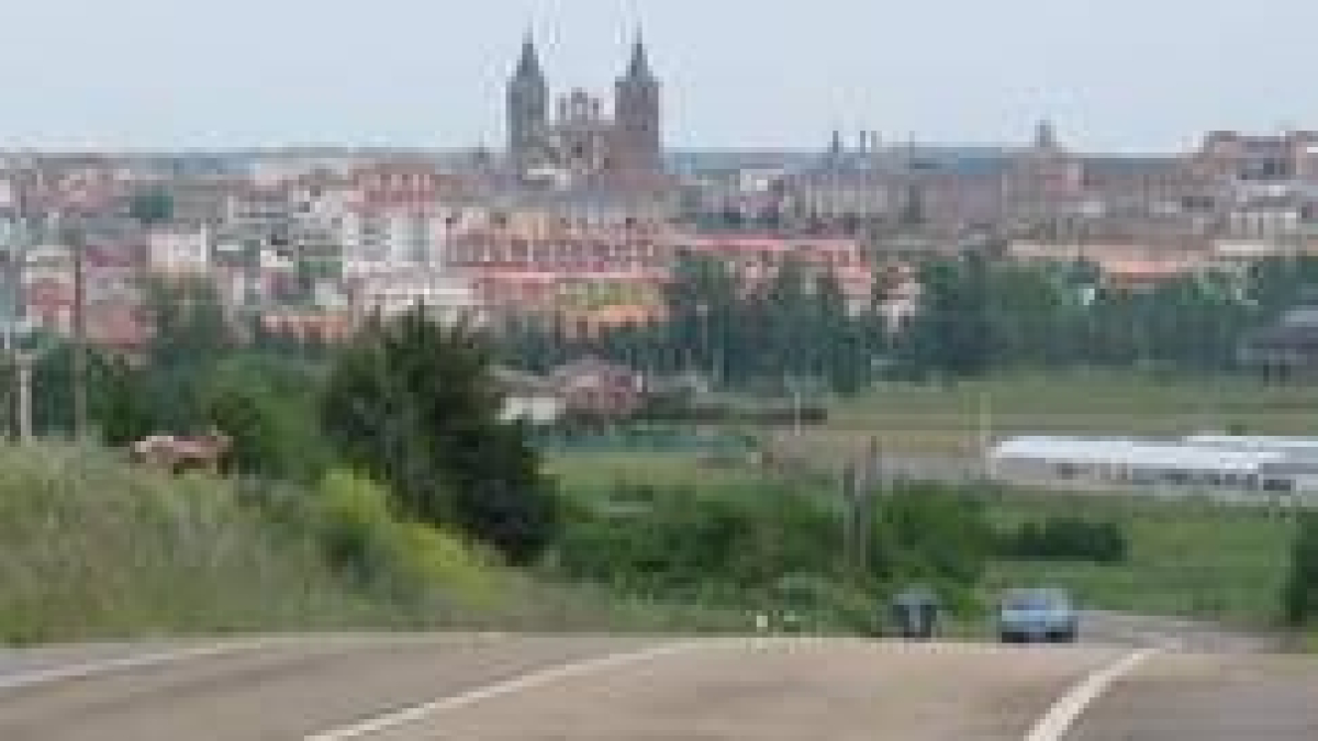 Un vehículo circula por la carretera Astorga-Nogarejas con la capital maragata al fondo de la imagen