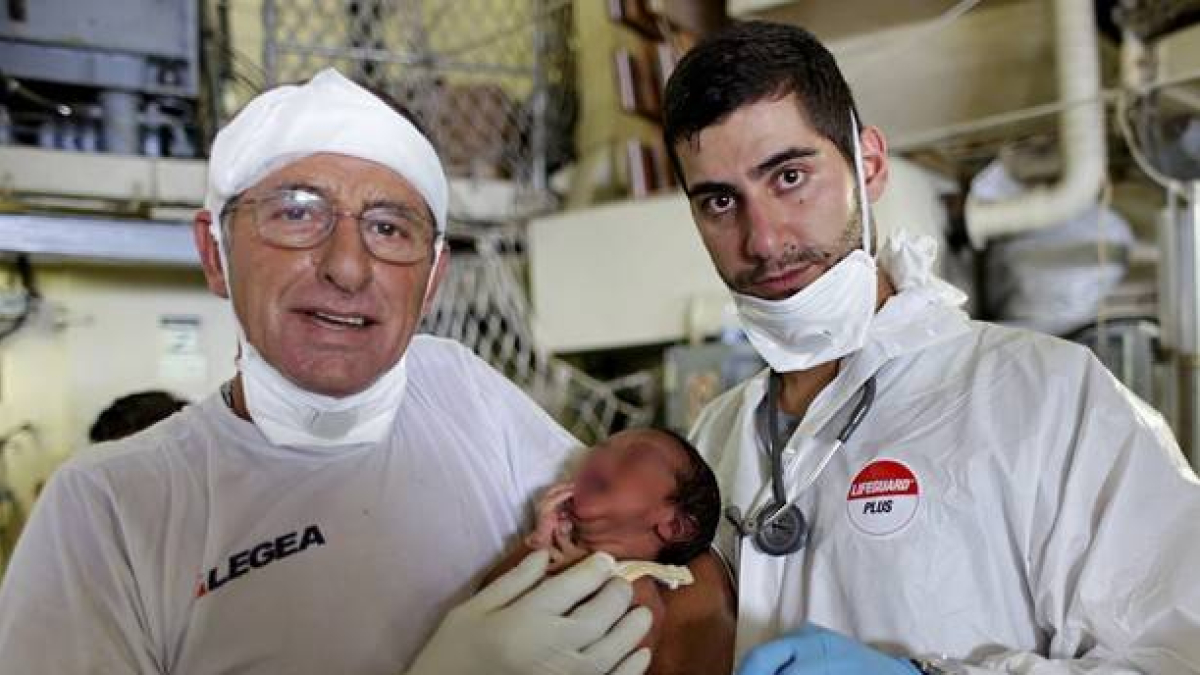 Personal de la Marina Militare muestra, este lunes, al bebé nacido hace cinco días en una barca que transportaba a 284 refugiados que fueron rescatados en la costa de Sicilia.