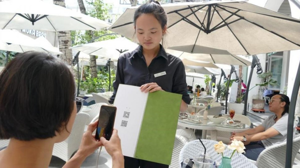 Una joven paga su consumición en un terraza de Shanghái con el teléfono móvil.