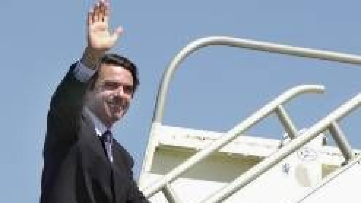 Aznar saluda mientras sube la escalerilla de un avión