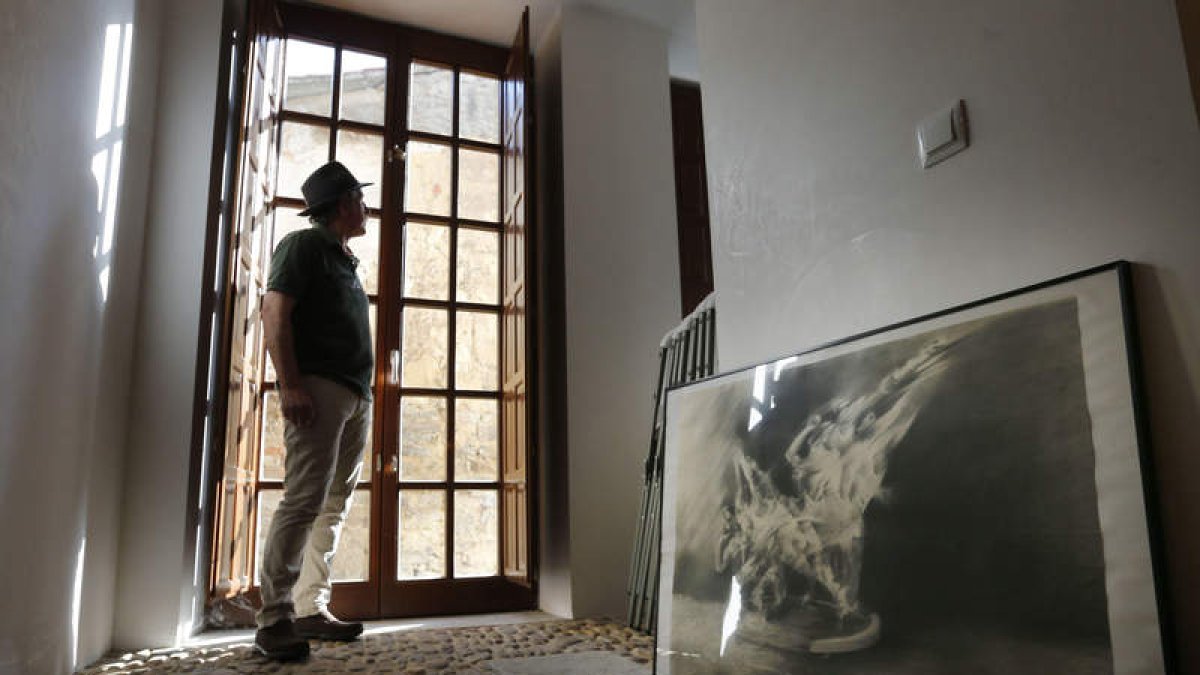 Sendo mira por una de las ventanas de la Casa Panero, mientras una de sus obras—expuestas hasta el 20 de agosto, en la capital maragata— invita a reflexionar sobre el movimiento, la erosión, la agresión de nuestro tiempo. Sendo se para, mira,
