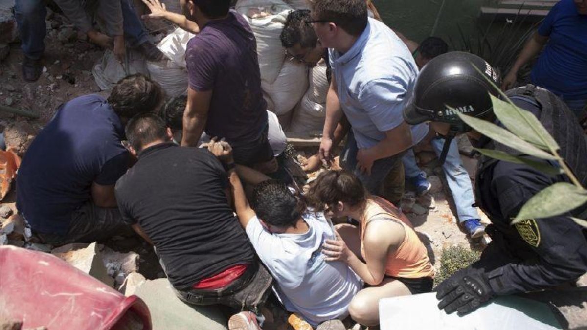 Los equipos de rescate sacan con vida a un hombre de entre los escombros.