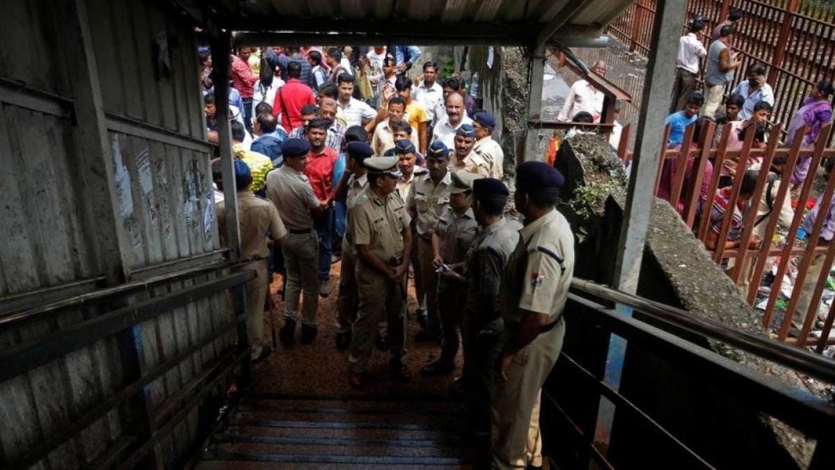 Policías inspeccionan el lugar de la estampida en un puente de peatones sobre las vías de tren, en Bombay, el 29 de septiembre