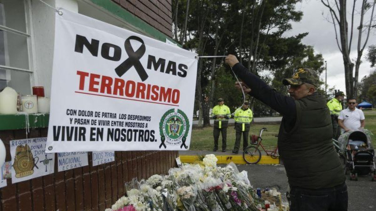 Un hombre extiende una pancarta durante un homenaje a los cadetes muertos por la explosion del carro bomba contra la Escuela de Cadetes de la Policia General Santander en un ataque atribuido a la guerrilla del ELN.