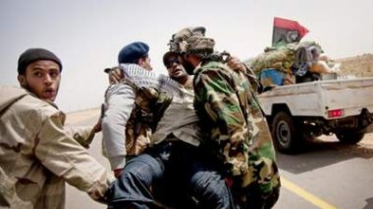 Rebeldes libios trasladan a un compatriota herido en un ataque de las fuerzas de Gadafi.