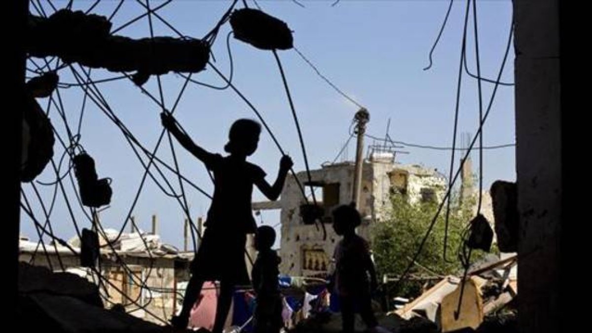 Unos niños palestinos juegan en las ruinas de un edificio destruido.