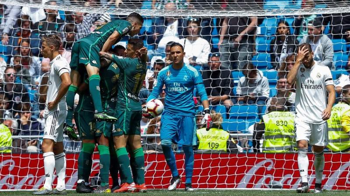 Los futbolistas del Betis celebran el segundo gol mientras se lamentan los jugadores del Madrid. EMILIO NARANJO