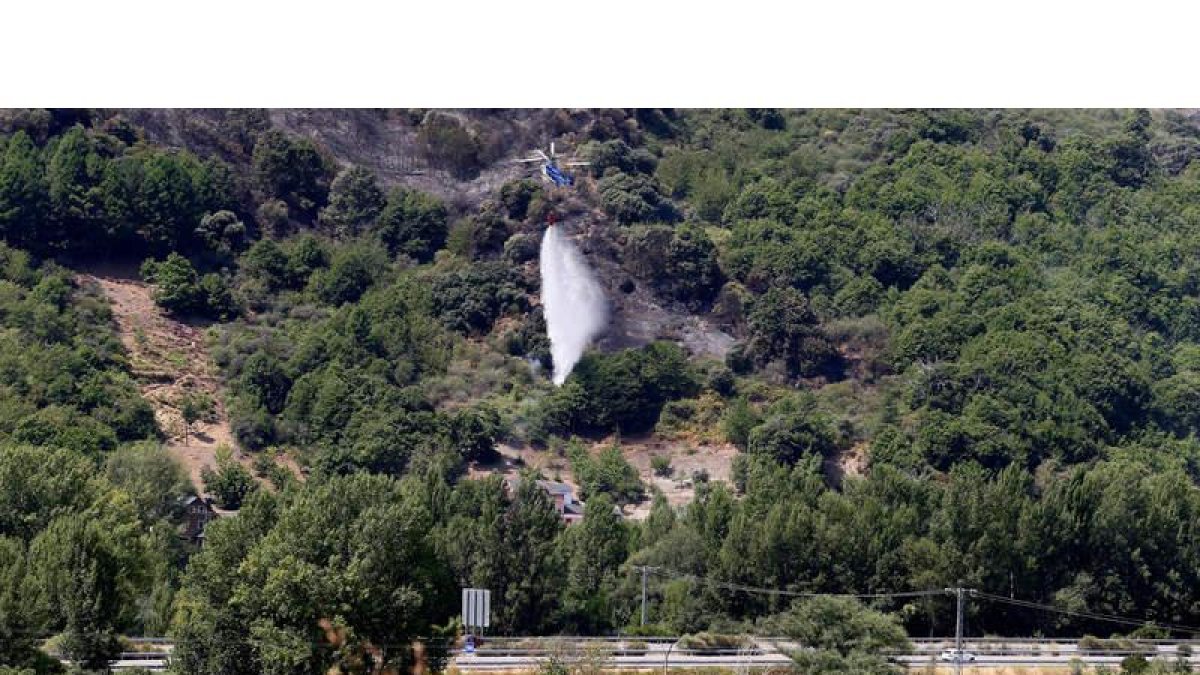 Un helicóptero refresca la zona del incendio registrado ayer en los montes de Corullón.