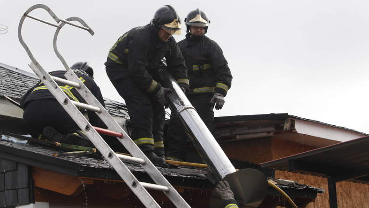 Los bomberos retiran la chimenea de la cubierta afectada por el fuego.