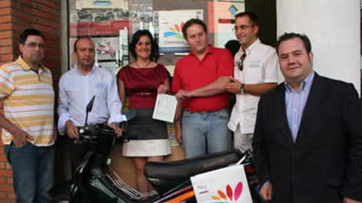 El ganador posa con la moto y con los asistentes al acto.