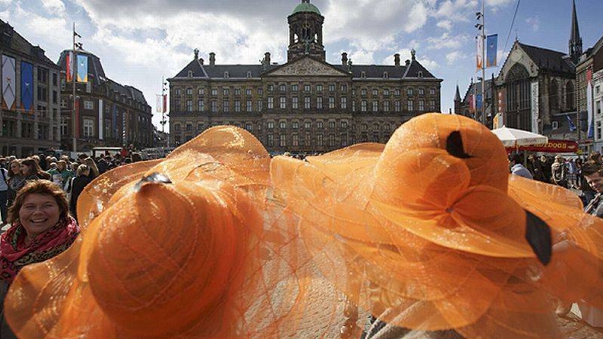Dos mujeres con sombrero naranja asisten a los preparativos de la ceremonia de llegada al trono del rey Guillermo.
