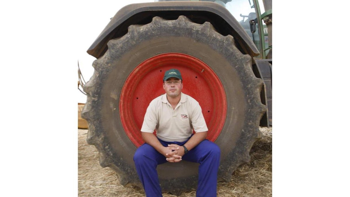 El mansillés David Rodríguez posa en la rueda de su tractor.